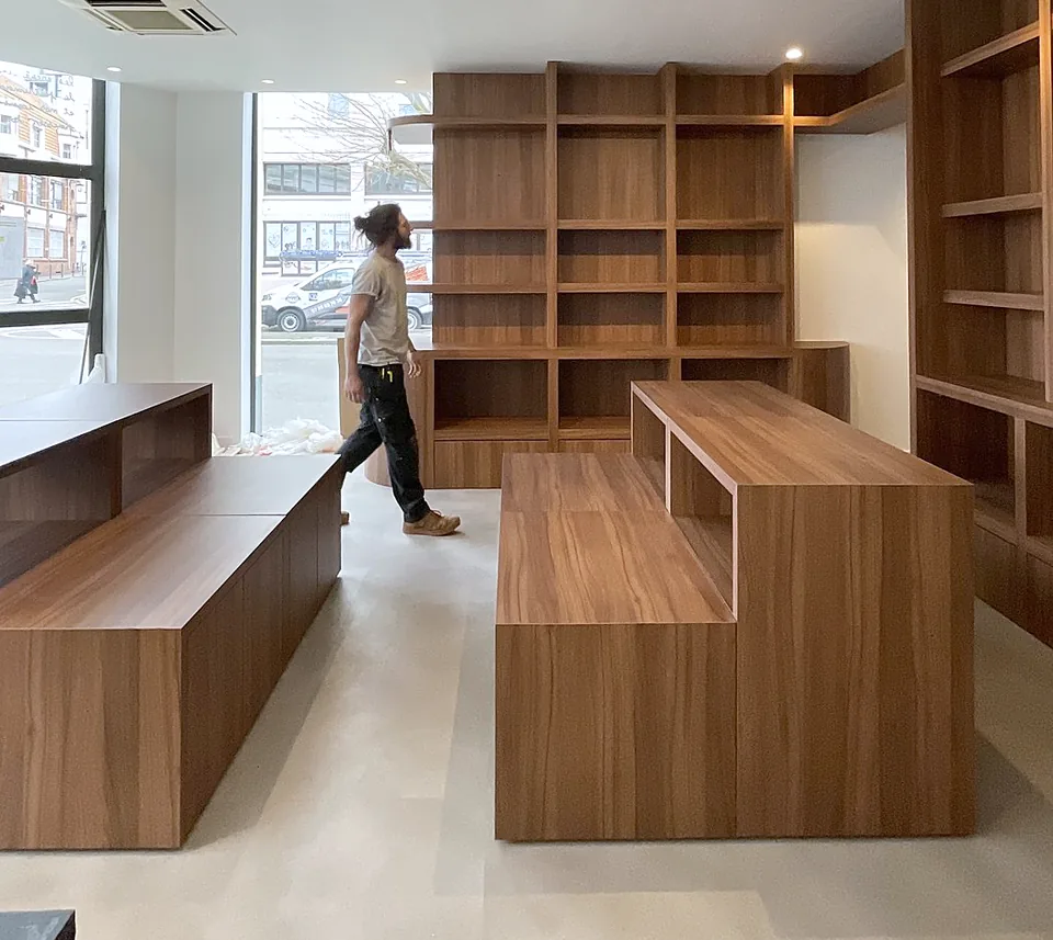 Agencement sur mesure en bois d'une boutique : bibliothèques et gondoles, pendant la pose